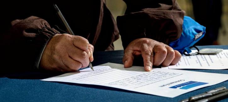 Adult hands grasp a pen and write comments on paper comment form.